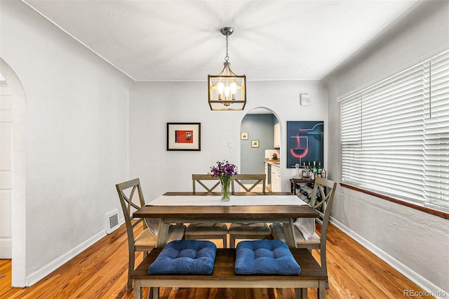 706 S Lincoln St, Denver, CO 80209 - dining room featuring arched walkways, a chandelier, and light wood finished floors