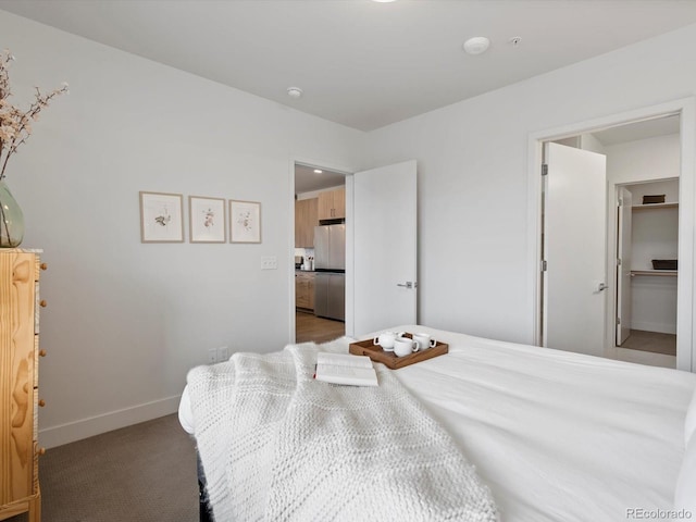 bedroom featuring baseboards, freestanding refrigerator, and a spacious closet
