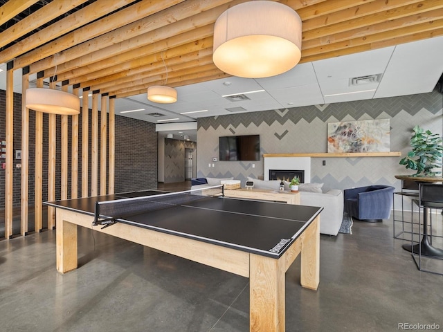 game room featuring finished concrete flooring, a fireplace, and visible vents