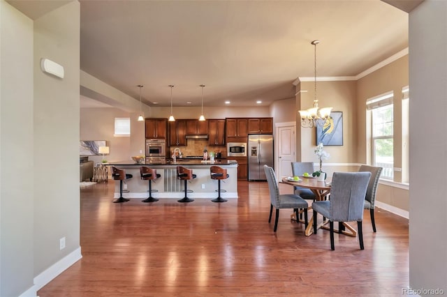 dining space with dark hardwood / wood-style flooring, an inviting chandelier, crown molding, and sink