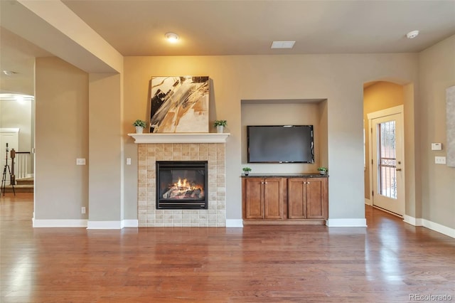 unfurnished living room featuring wood-type flooring and a tile fireplace