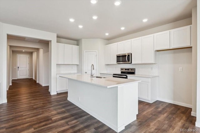 14406 Ranch St, Mead, CO 80504 - kitchen with appliances with stainless steel finishes, tasteful backsplash, white cabinetry, a kitchen island with sink, and light countertops
