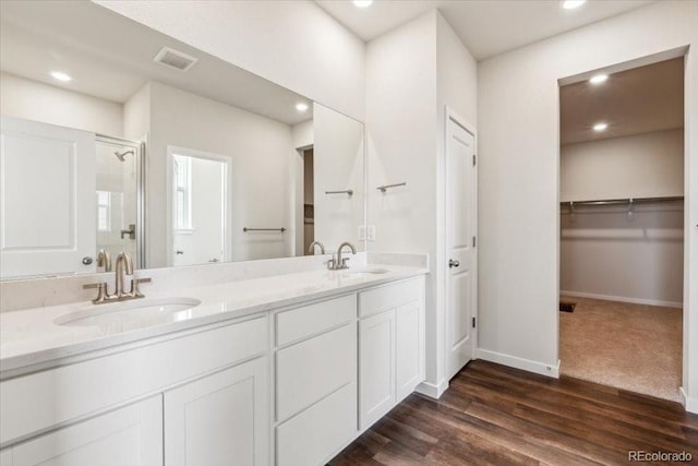 14406 Ranch St, Mead, CO 80504 - bathroom featuring double vanity, a stall shower, a walk in closet, wood finished floors, and recessed lighting