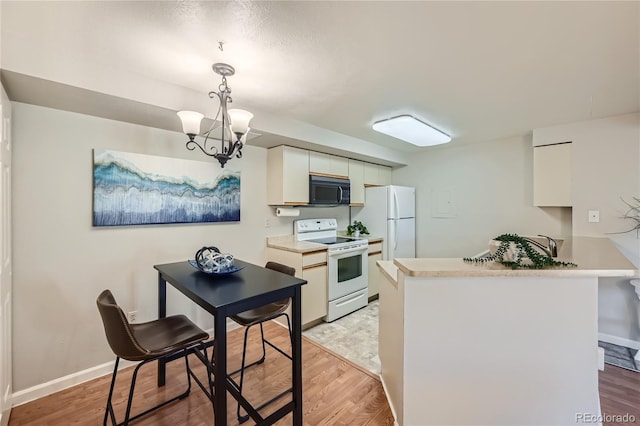 kitchen featuring white appliances, an inviting chandelier, hanging light fixtures, light wood-type flooring, and kitchen peninsula