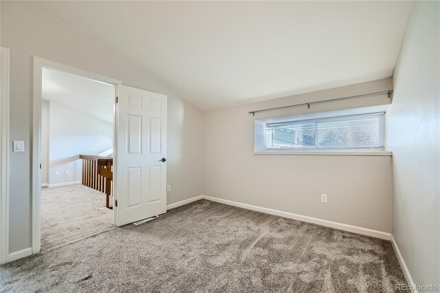 carpeted empty room featuring lofted ceiling