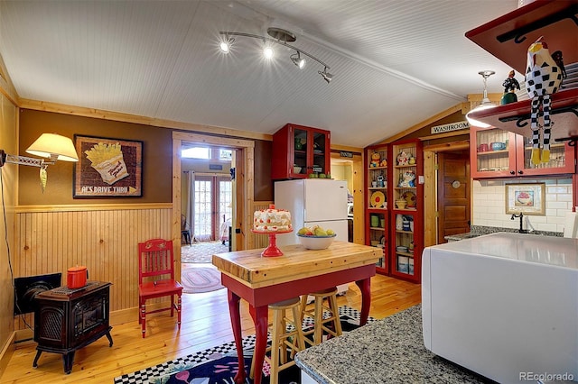 80 Meadow Ln, Bailey, CO 80421 - dining area featuring light wood-style floors, wainscoting, a wood stove, vaulted ceiling, and rail lighting