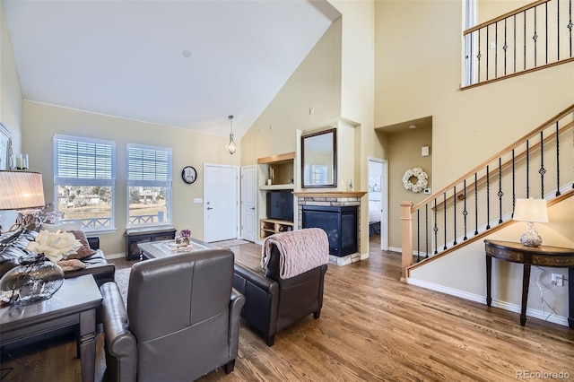 living room with wood-type flooring, high vaulted ceiling, and a fireplace