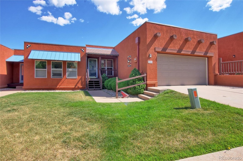 adobe home featuring a garage and a front yard