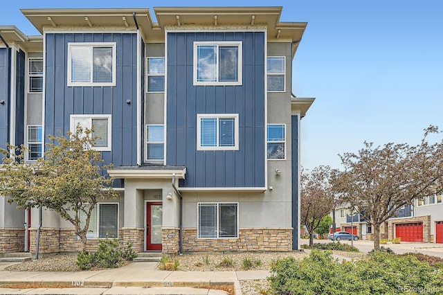 view of front of home featuring board and batten siding, stone siding, and stucco siding