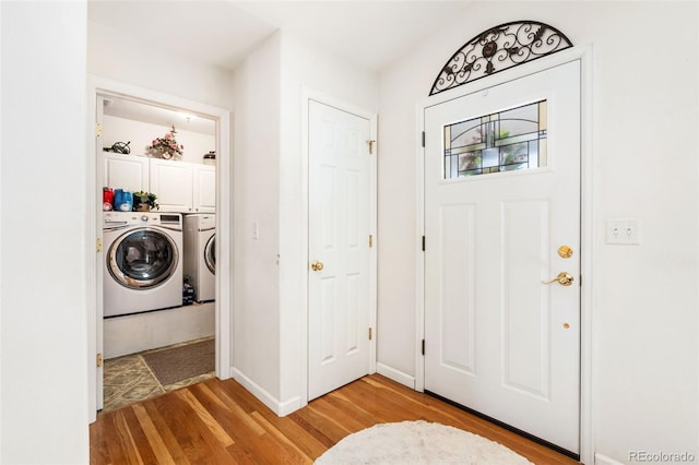 foyer entrance with washer and dryer and light hardwood / wood-style flooring