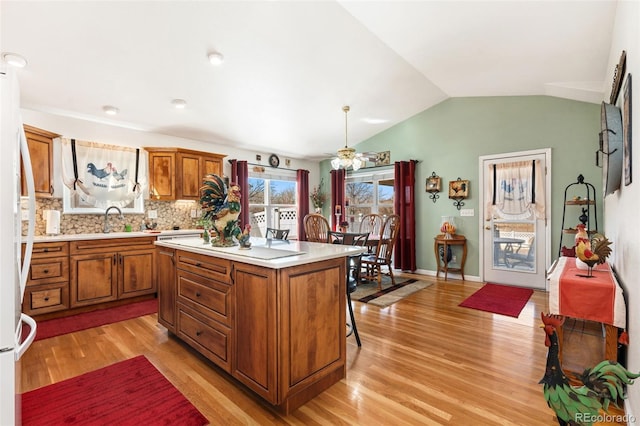 kitchen featuring lofted ceiling, sink, a kitchen island, pendant lighting, and light hardwood / wood-style floors