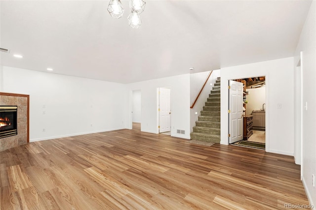 unfurnished living room with a tile fireplace and hardwood / wood-style floors