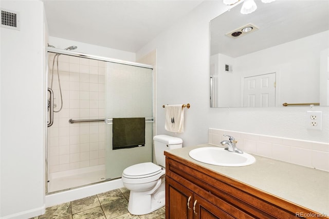 bathroom with toilet, vanity, and a shower with shower door