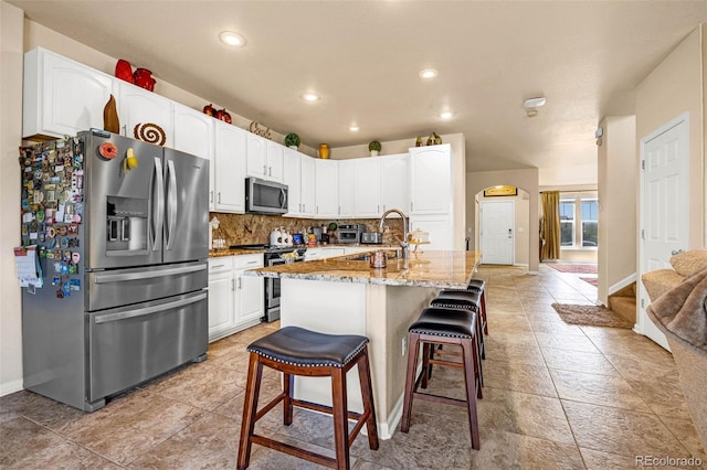 8004 Brittinger Way, Colorado Springs, CO 80951 - kitchen featuring stainless steel appliances, light stone countertops, arched walkways, white cabinets, and recessed lighting