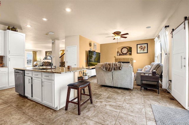 8004 Brittinger Way, Colorado Springs, CO 80951 - kitchen with dishwasher, open floor plan, a breakfast bar, a barn door, and white cabinets