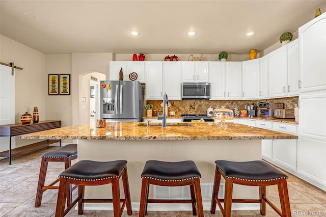 8004 Brittinger Way, Colorado Springs, CO 80951 - kitchen featuring appliances with stainless steel finishes, white cabinetry, a breakfast bar area, light stone counters, and tasteful backsplash