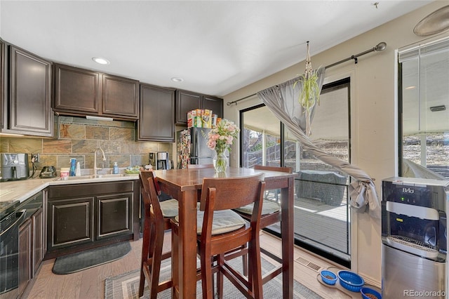 kitchen featuring electric stove, light countertops, freestanding refrigerator, a sink, and dark brown cabinets