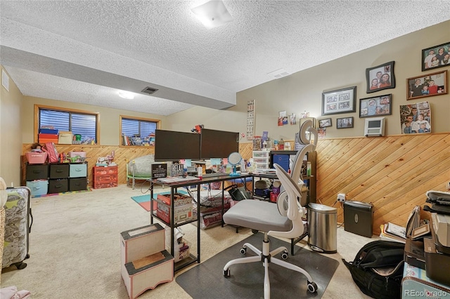 office area with carpet floors, wooden walls, visible vents, and a textured ceiling