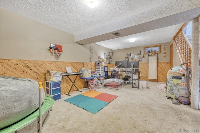 exercise room featuring visible vents, a wainscoted wall, wooden walls, and a textured ceiling