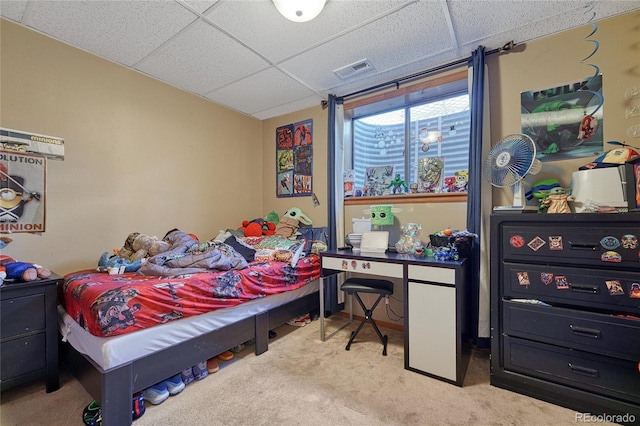 carpeted bedroom with visible vents and a drop ceiling