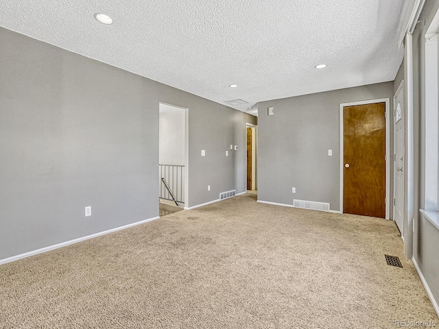 carpeted spare room with baseboards, visible vents, a textured ceiling, and recessed lighting