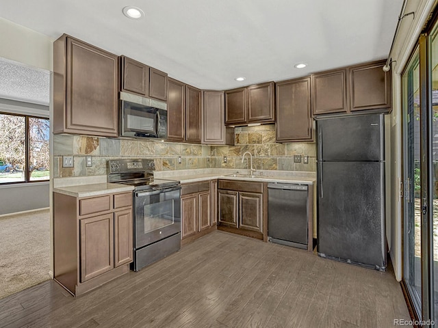 kitchen with a sink, freestanding refrigerator, dishwashing machine, range with electric stovetop, and light countertops