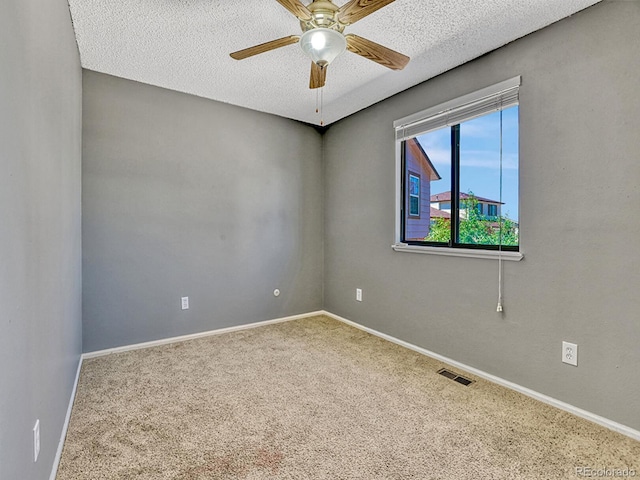 spare room with a ceiling fan, visible vents, carpet floors, and a textured ceiling