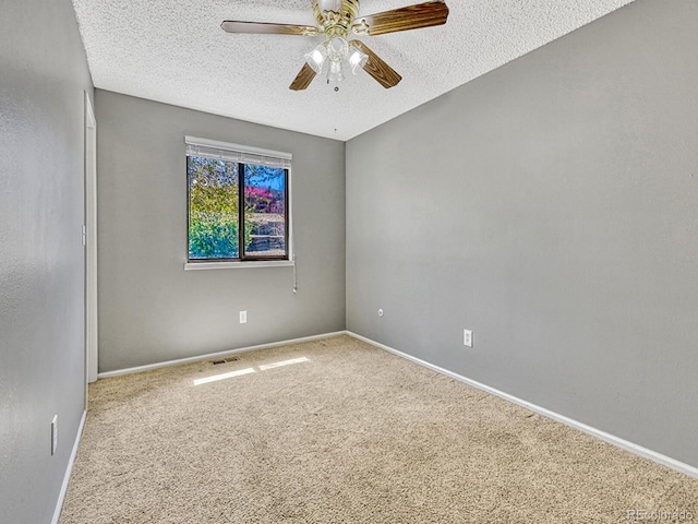 empty room featuring a textured ceiling, ceiling fan, carpet, baseboards, and visible vents