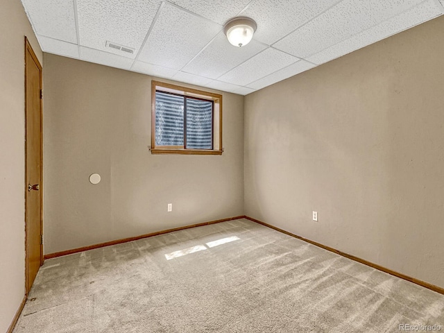 carpeted spare room with baseboards, visible vents, and a drop ceiling