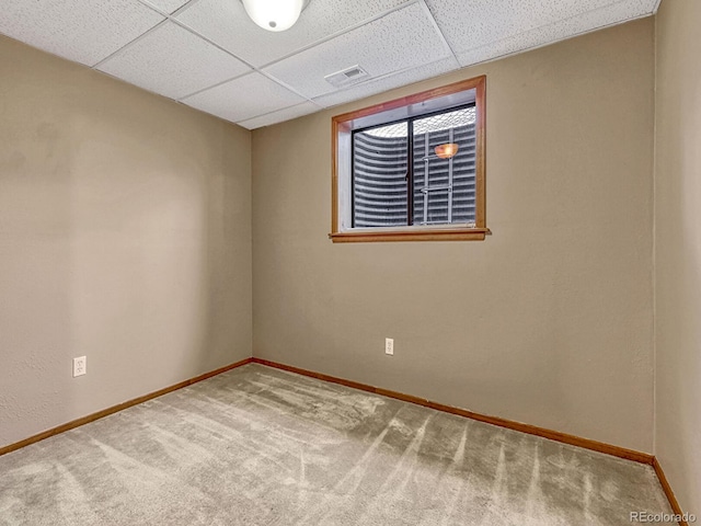 carpeted empty room featuring baseboards, a drop ceiling, and visible vents