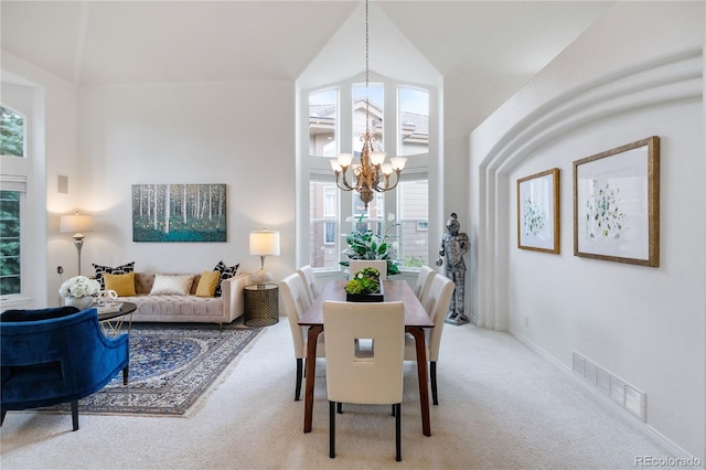 carpeted dining area with high vaulted ceiling and a chandelier