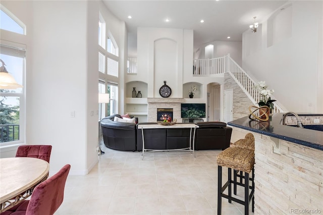 living room with a fireplace, light tile patterned floors, a wealth of natural light, and a towering ceiling