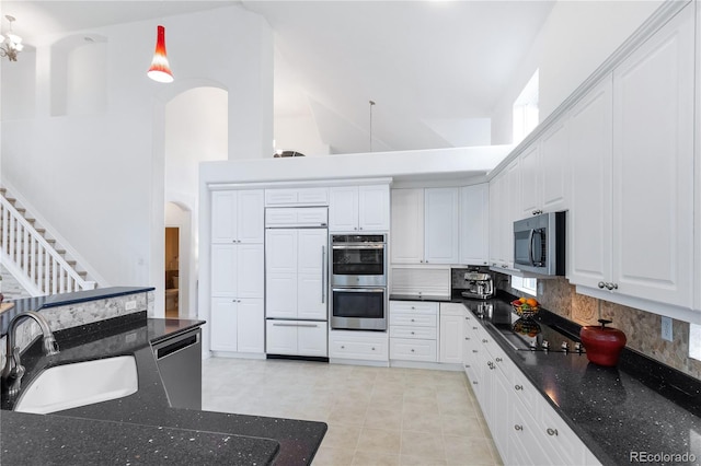 kitchen featuring light tile patterned flooring, backsplash, sink, a towering ceiling, and stainless steel appliances