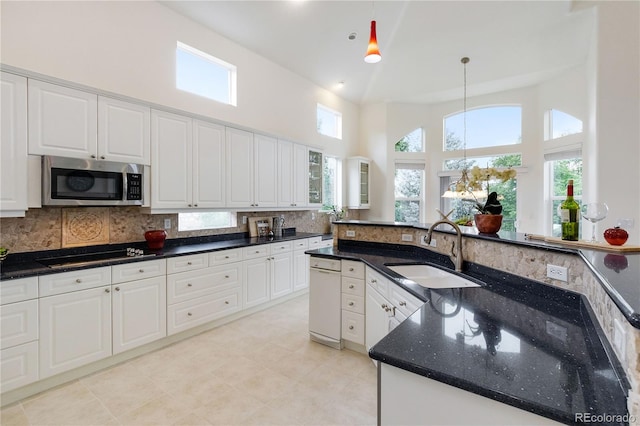 kitchen with pendant lighting, black cooktop, white cabinetry, light tile patterned floors, and sink