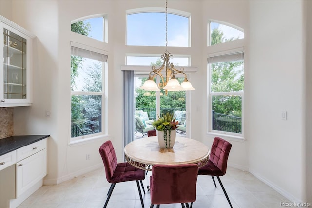 tiled dining area featuring a high ceiling, plenty of natural light, and a chandelier