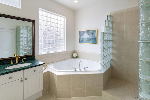 bathroom featuring tiled tub, tile patterned floors, and vanity