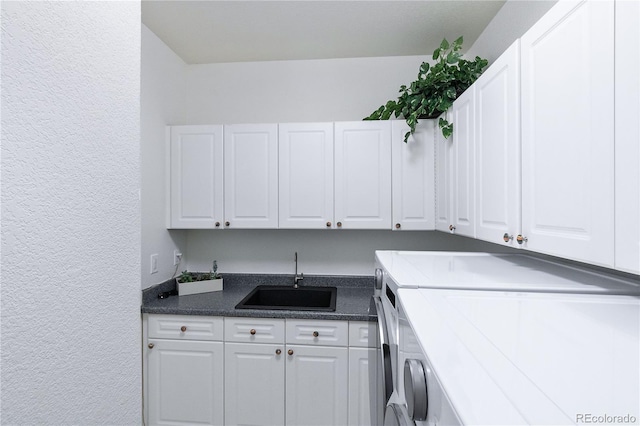 laundry room featuring sink, washer and clothes dryer, and cabinets