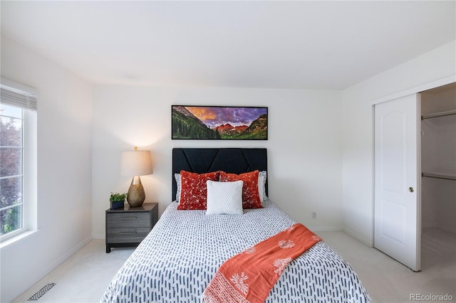 bedroom with a closet, light carpet, and multiple windows