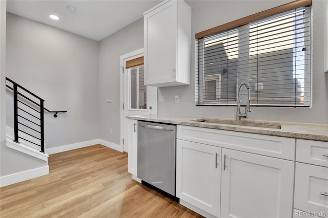 kitchen with white cabinets, dishwasher, light wood-style floors, and a sink