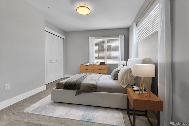 carpeted bedroom featuring baseboards and a closet