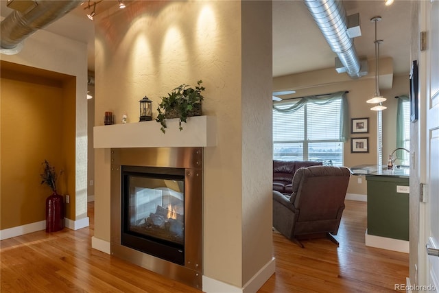 interior space featuring a multi sided fireplace, sink, and hardwood / wood-style flooring