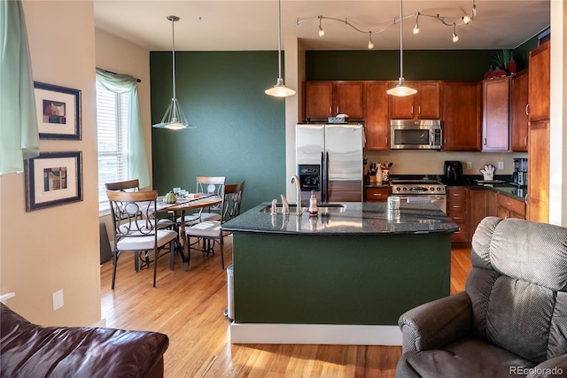 kitchen featuring sink, stainless steel appliances, pendant lighting, and an island with sink