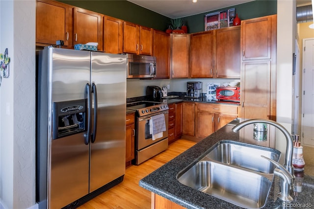 kitchen featuring appliances with stainless steel finishes, sink, and light hardwood / wood-style flooring