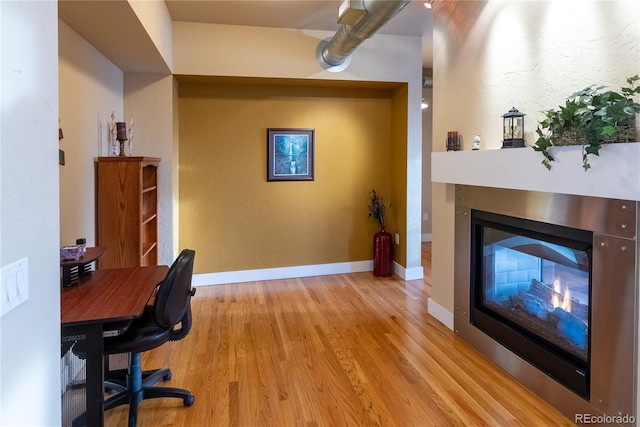 home office featuring light hardwood / wood-style flooring and a multi sided fireplace