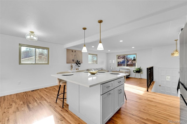 kitchen featuring pendant lighting, a center island, a kitchen bar, and light hardwood / wood-style floors