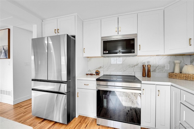 kitchen featuring light hardwood / wood-style floors, white cabinetry, stainless steel appliances, and tasteful backsplash