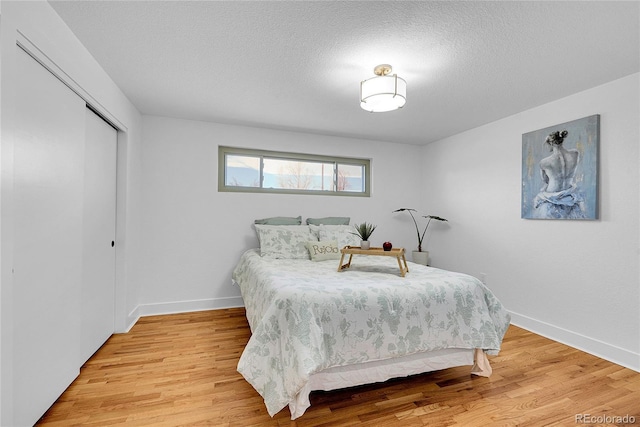 bedroom with light wood-type flooring, a textured ceiling, and a closet