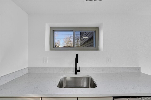 kitchen with dishwashing machine, light stone counters, and sink