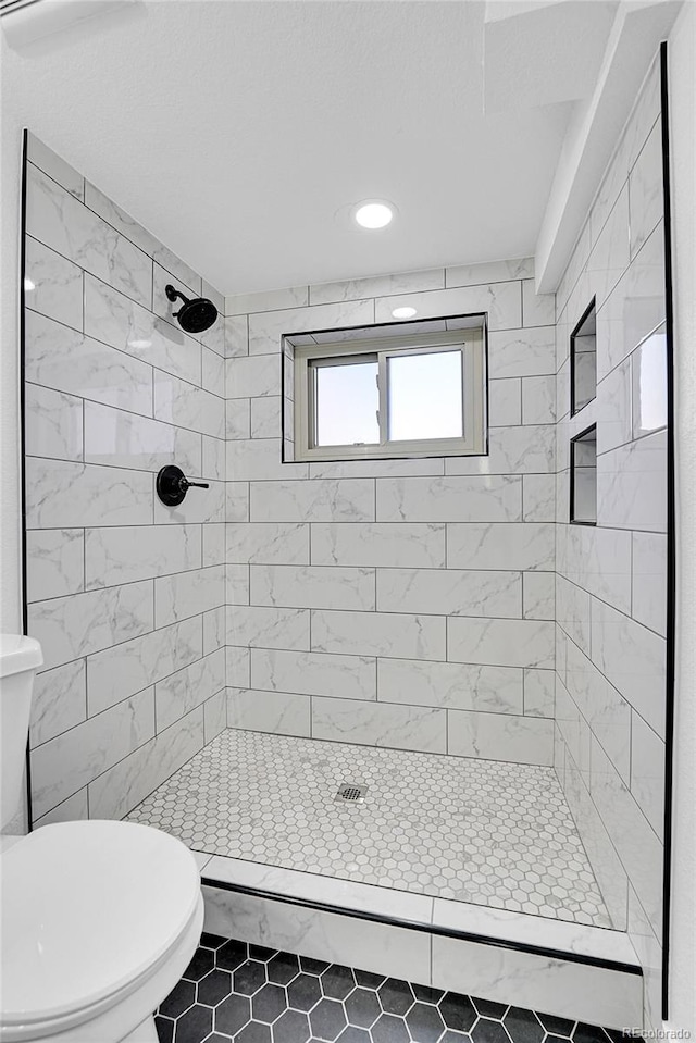 bathroom with tile patterned floors, toilet, and a tile shower