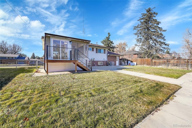 rear view of house featuring a sunroom, central AC, and a lawn